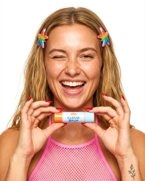 Model shot: a smiling woman holding a lip balm